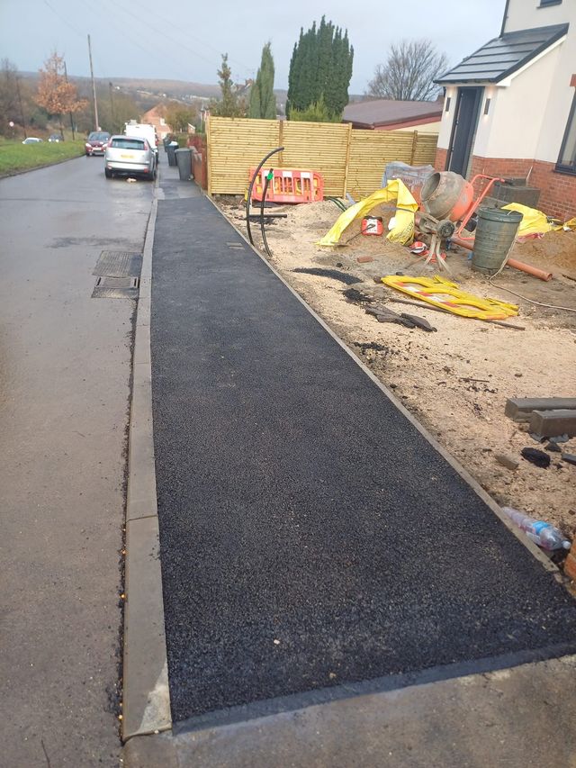 New tarmac laid along a footway behind new kerbs in Sheffield