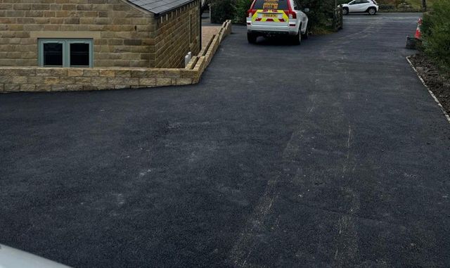 Large black tarmac driveway with parking spaces beside a stone house in Crosspool, Sheffield