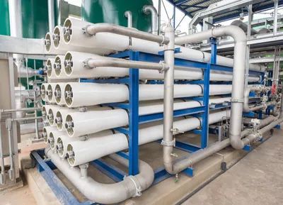 Industrial water filtration system with white cylindrical filters and blue metal supports.