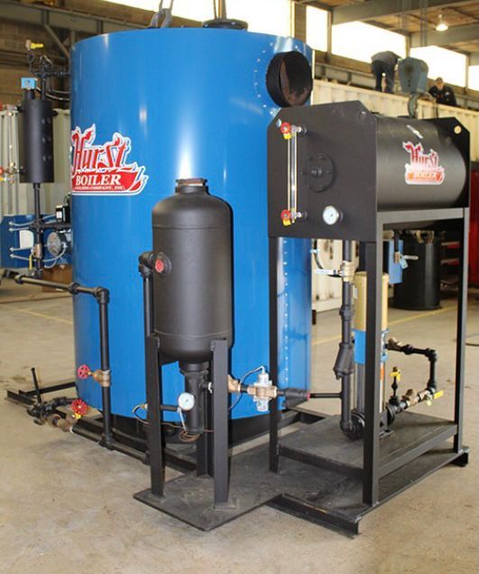 Blue and black Hurst boiler system. Cylindrical tanks with pipes, gauges, and valves, in an industrial setting.