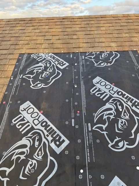 Black RhinoRoof U20 synthetic underlayment installed on a residential roof, transitioning to existing asphalt shingles.