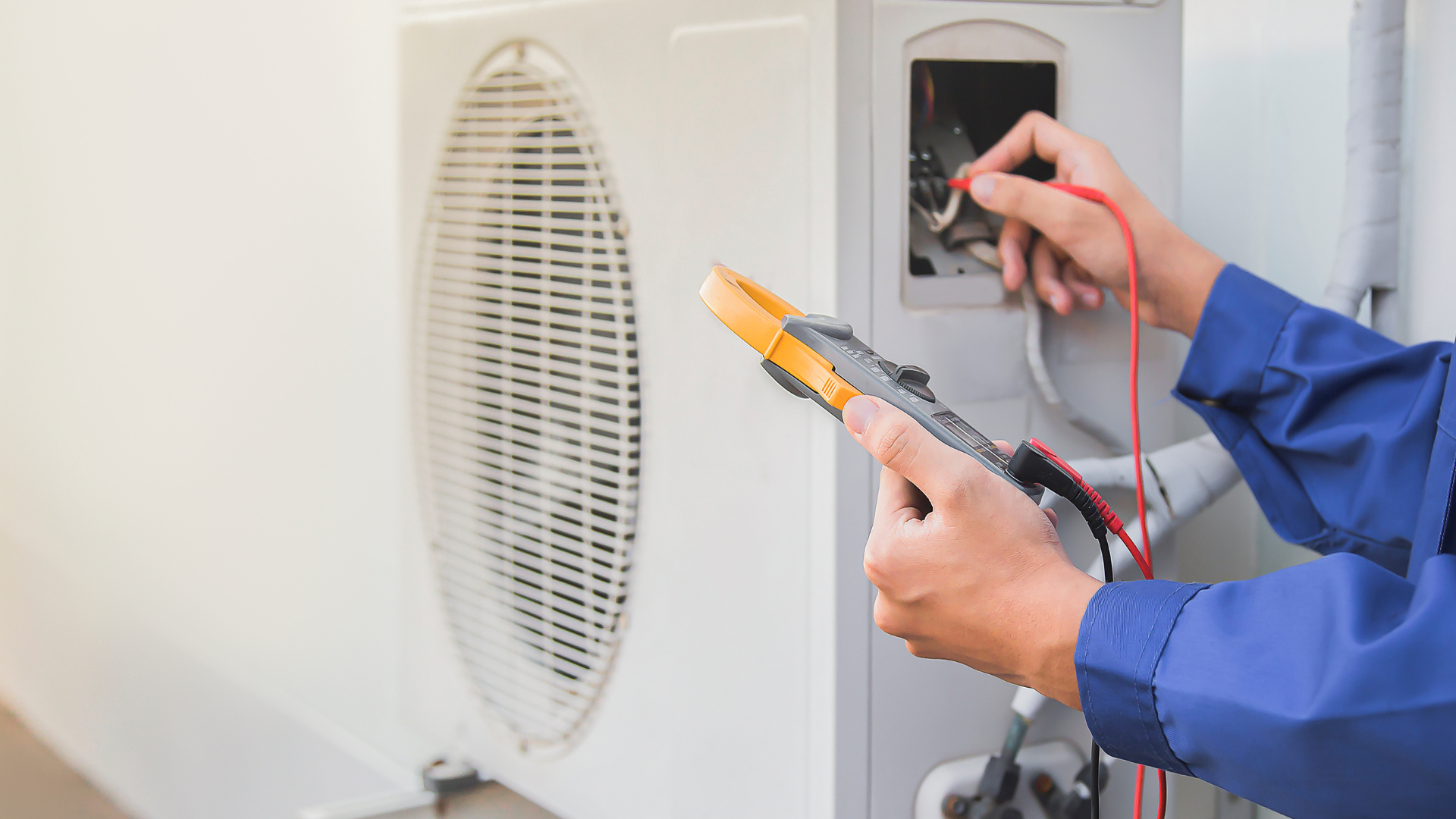 Technician testing electrical wiring inside a wall panel with a multimeter