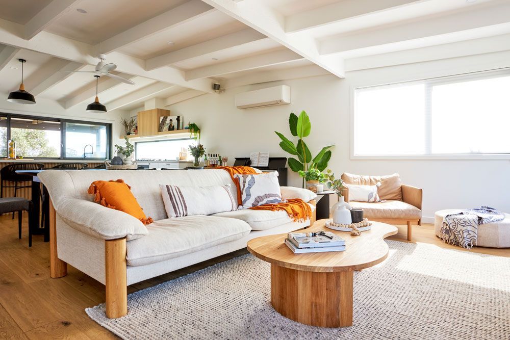 Bright living room with white beams, a light-colored sofa, and wood coffee table.