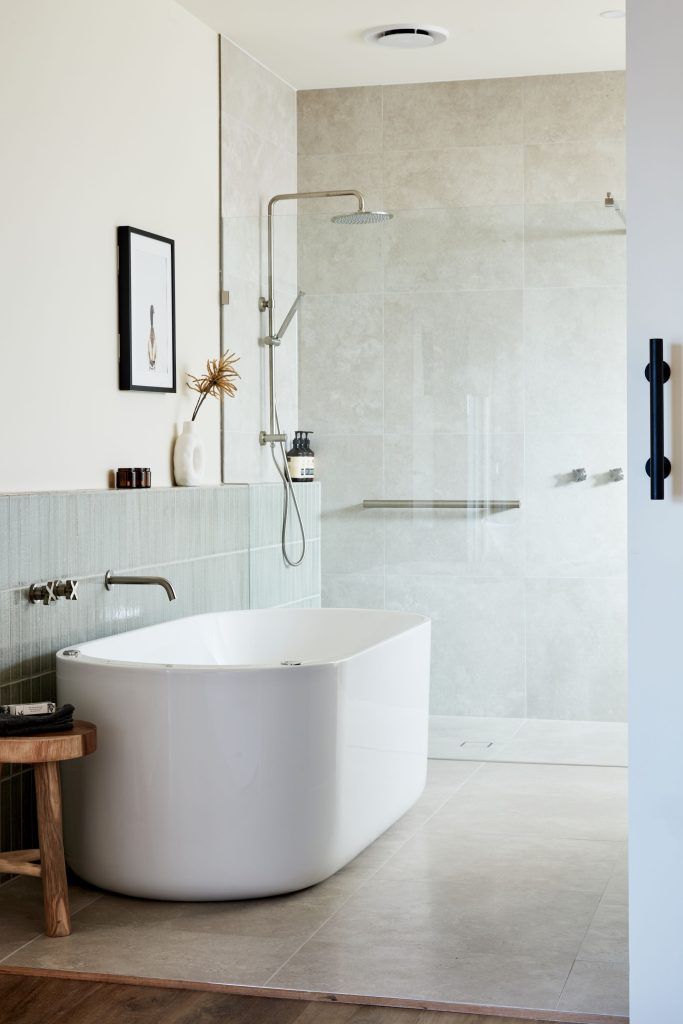 Modern bathroom with white tub, walk-in shower, and light gray tile.