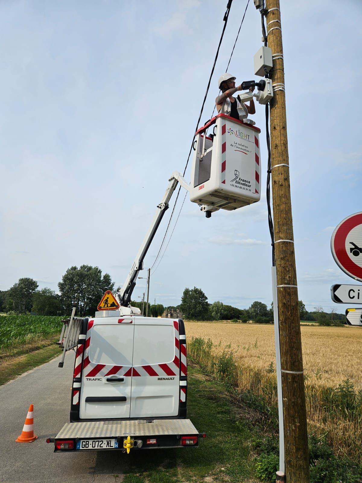 Une camionnette blanche est garée sur le bord de la route à côté d'un poteau.