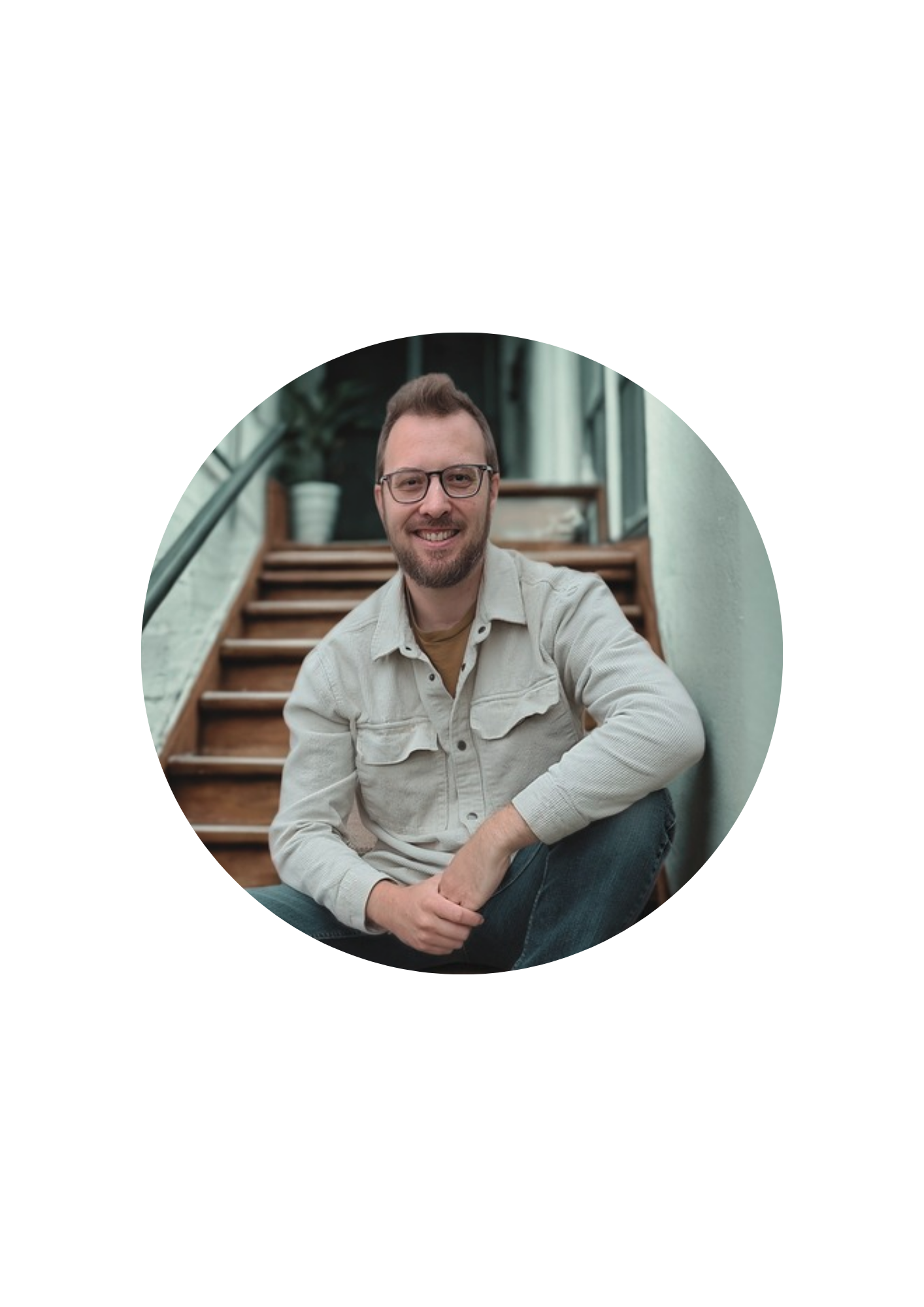 Owner of DC Tech on wooden steps, wearing a light beige shirt jacket, with a soft blurred background
