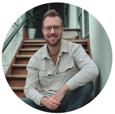 Owner of DC Tech sitting on wooden stairs in a light jacket and jeans, outdoors.