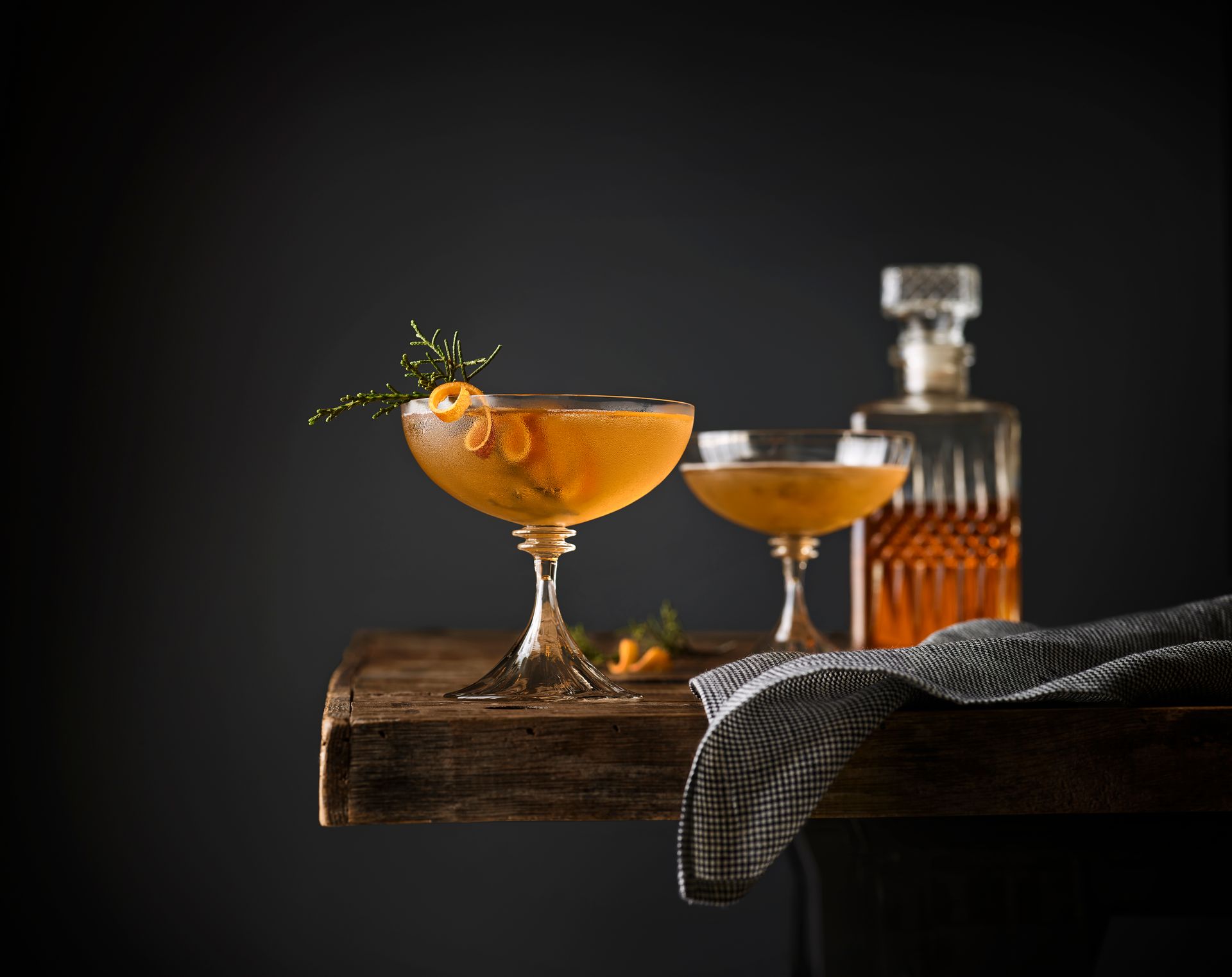 A Bottle of Whiskey and Two Glasses of Whiskey Are on A Wooden Table - Lee’s Summit, MO - Top Shelf Bartending Services, LLC