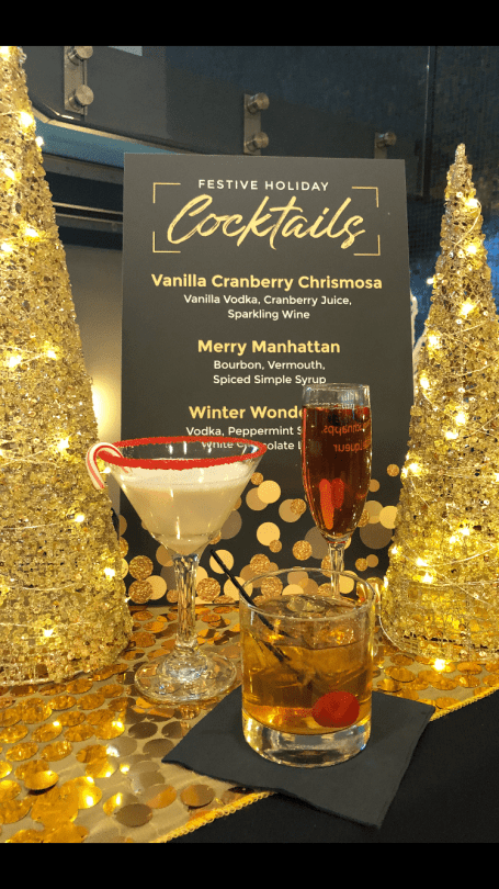 Two Cocktails Are Sitting on A Table Next to A Sign that Says Cocktails - Lee’s Summit, MO - Top Shelf Bartending Services, LLC