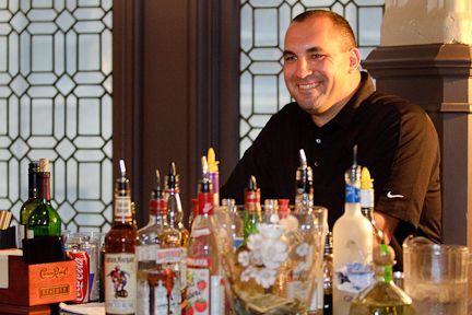 A Man Is Standing Behind a Bar Filled with Bottles of Alcohol - Lee’s Summit, MO - Top Shelf Bartending Services, LLC