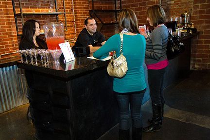 A Group of People Are Standing Around a Bar Talking to A Bartender - Lee’s Summit, MO - Top Shelf Bartending Services, LLC