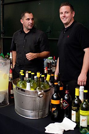 Two Men Are Standing in Front of A Table Full of Wine Bottles - Lee’s Summit, MO - Top Shelf Bartending Services, LLC