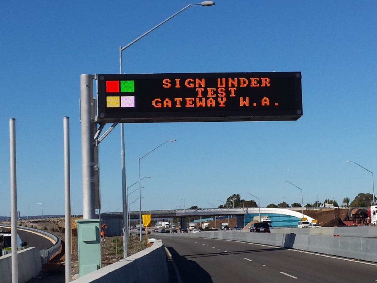 Highway sign reading “Sign under test” above a roadway and overpass