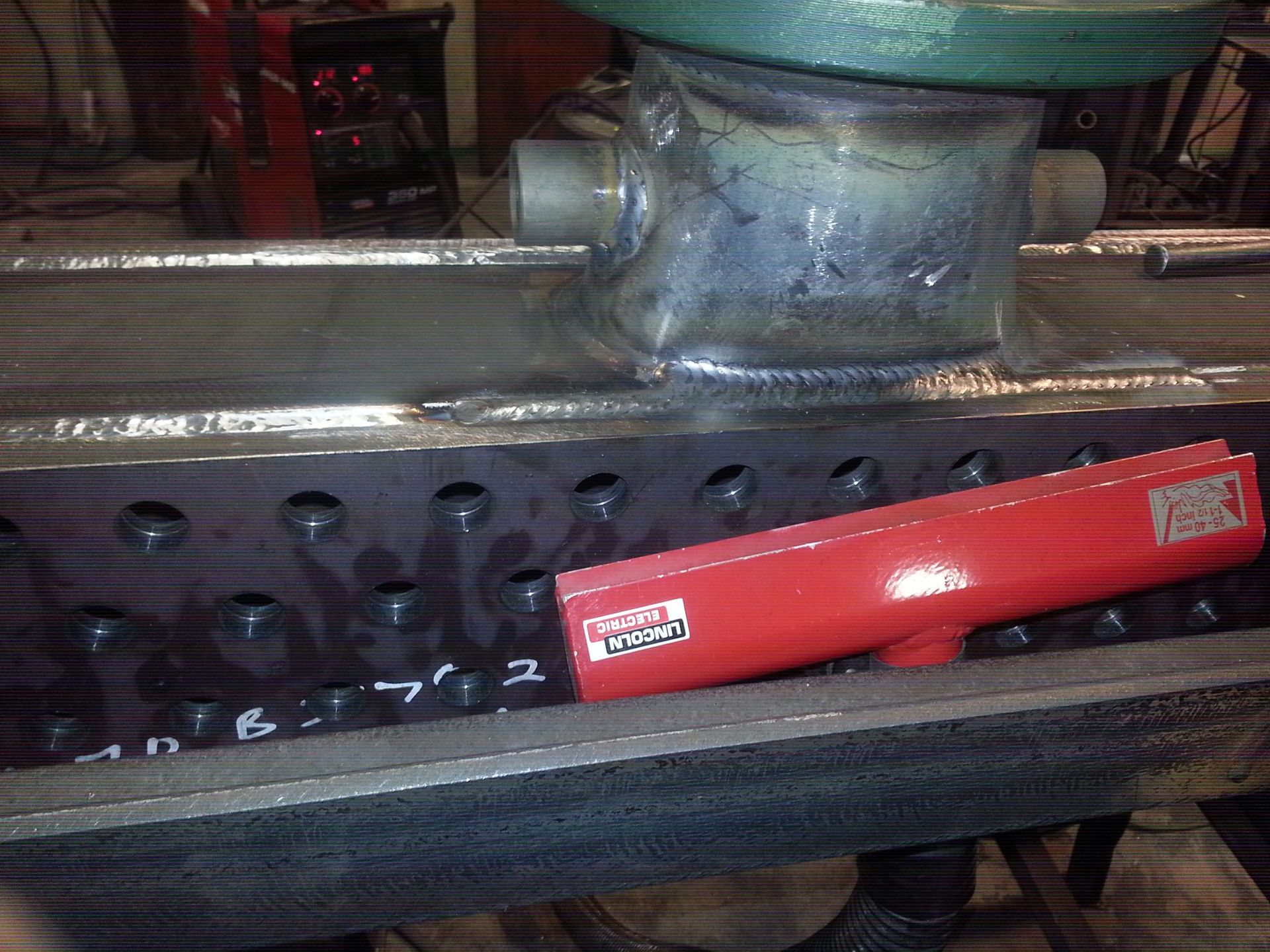 Red train car on a track beneath a glass platform inside a station or display case.