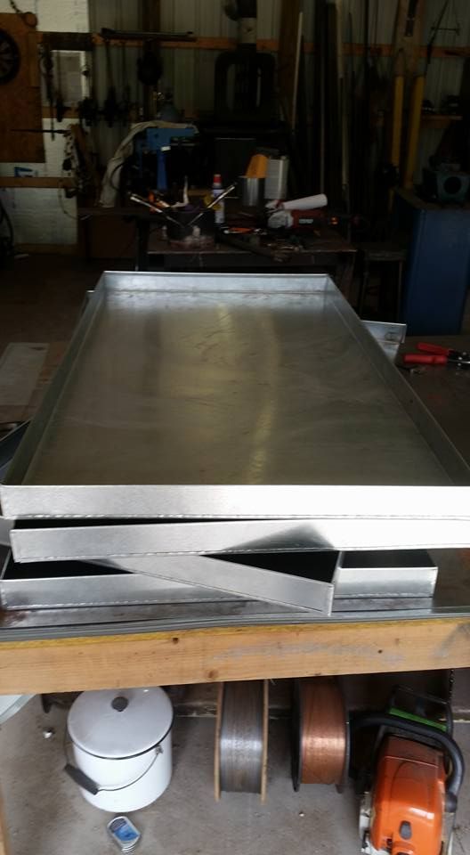Large metal worktable in a dim workshop with tools and machinery in the background.