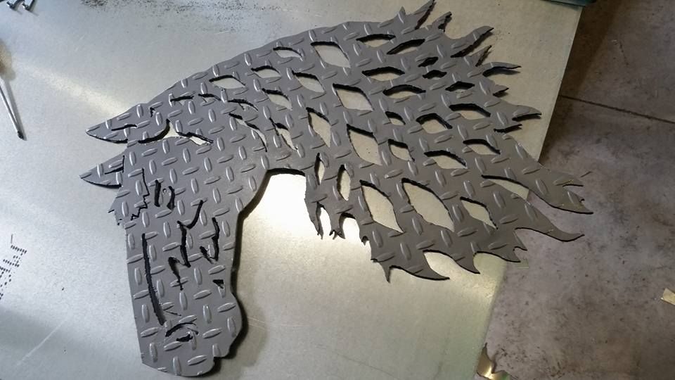 Metal horse head sculpture with a leafy mane, lying on a tiled floor