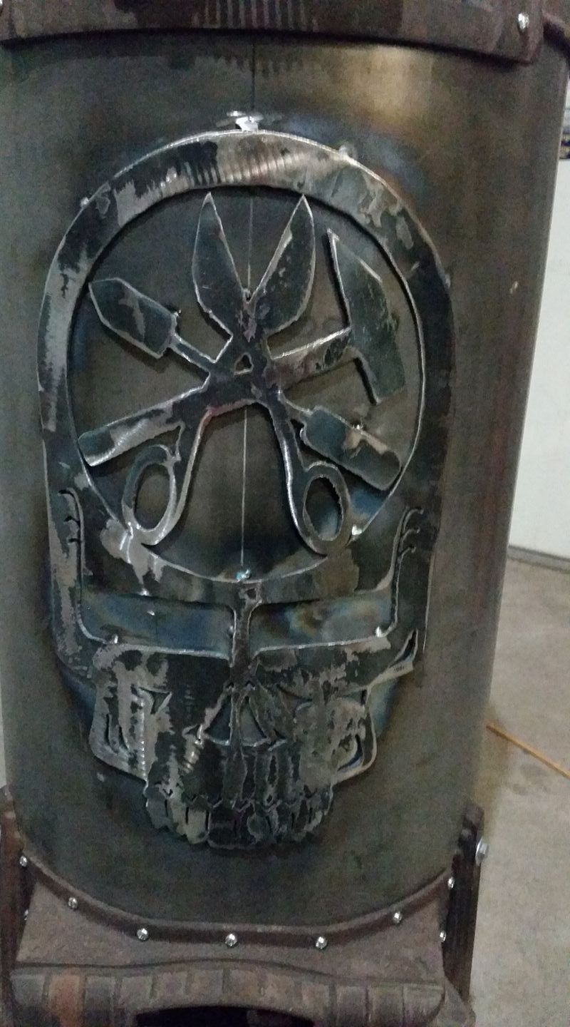 Dark metal cylinder with a worn skull-and-crossbones emblem and riveted bands