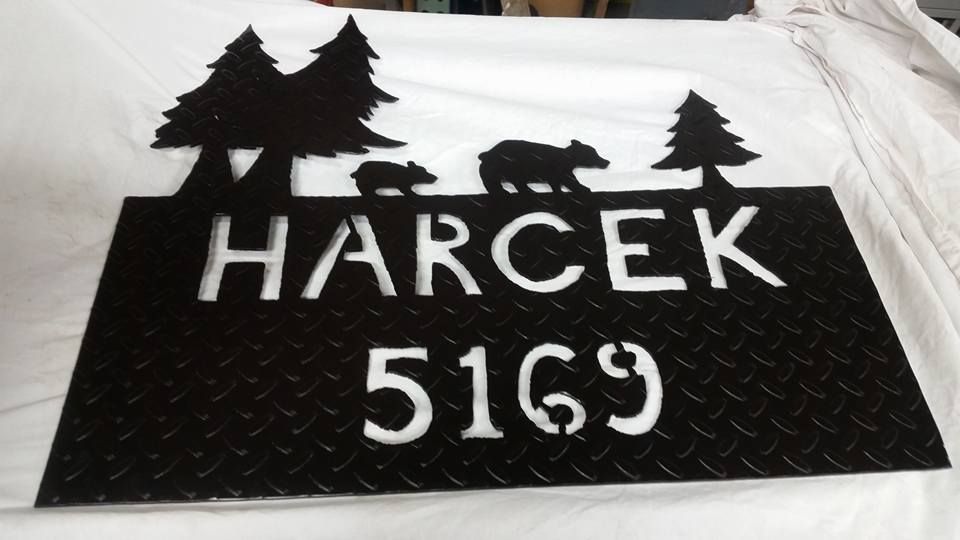 Black cutout sign with trees and the text “HARČEK 5169” on a white cloth background