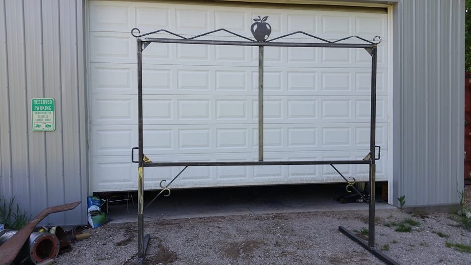 Metal gate frame in front of a white garage door beside a gray metal building.