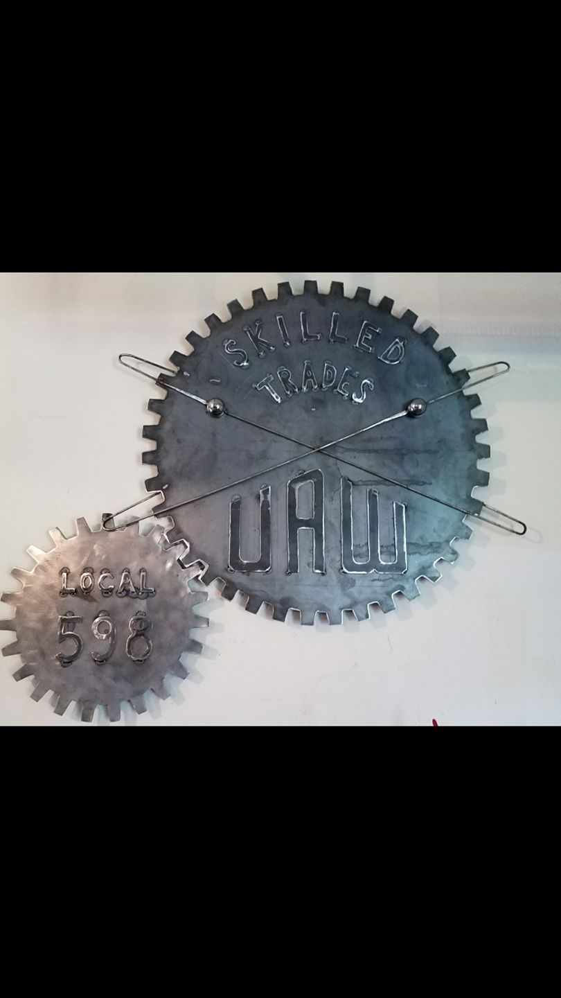 Two metal gears with cutout letters, one large gray gear overlapping a smaller silver gear on a white background