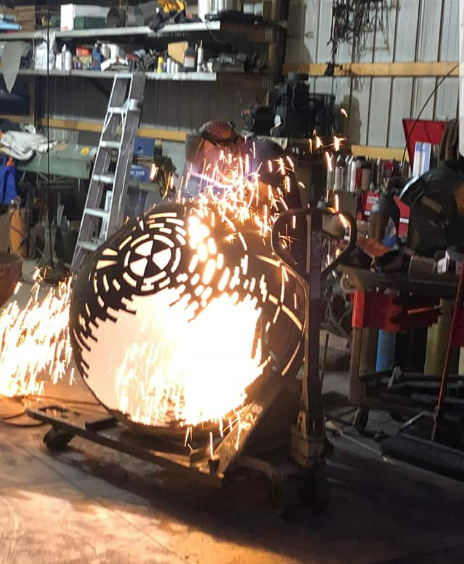 Workshop scene with a metal sculpture being cut by bright sparks from a torch