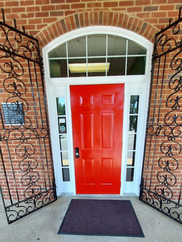A red door is surrounded by a wrought iron gate