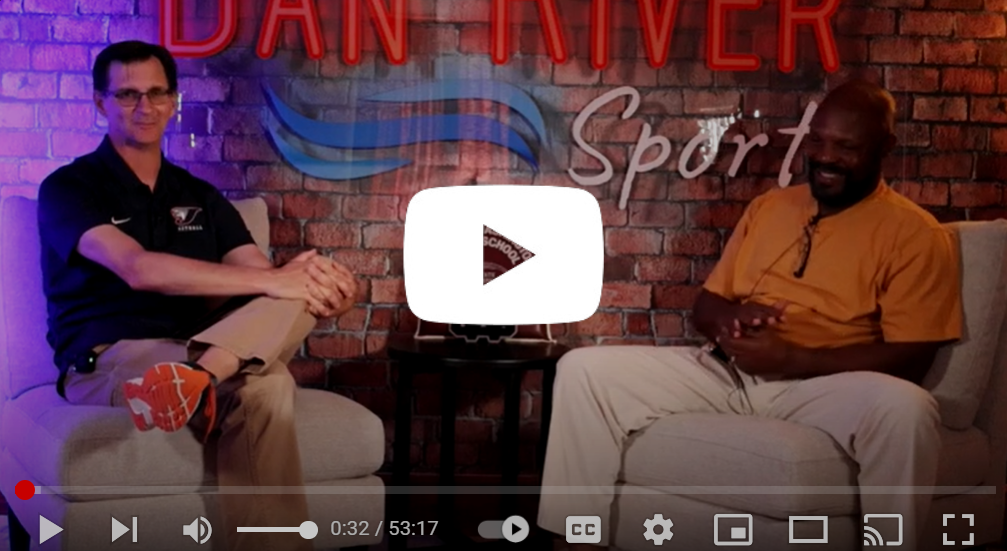 Two men are sitting in chairs in front of a brick wall.