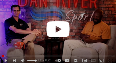 Two men are sitting in chairs in front of a brick wall.