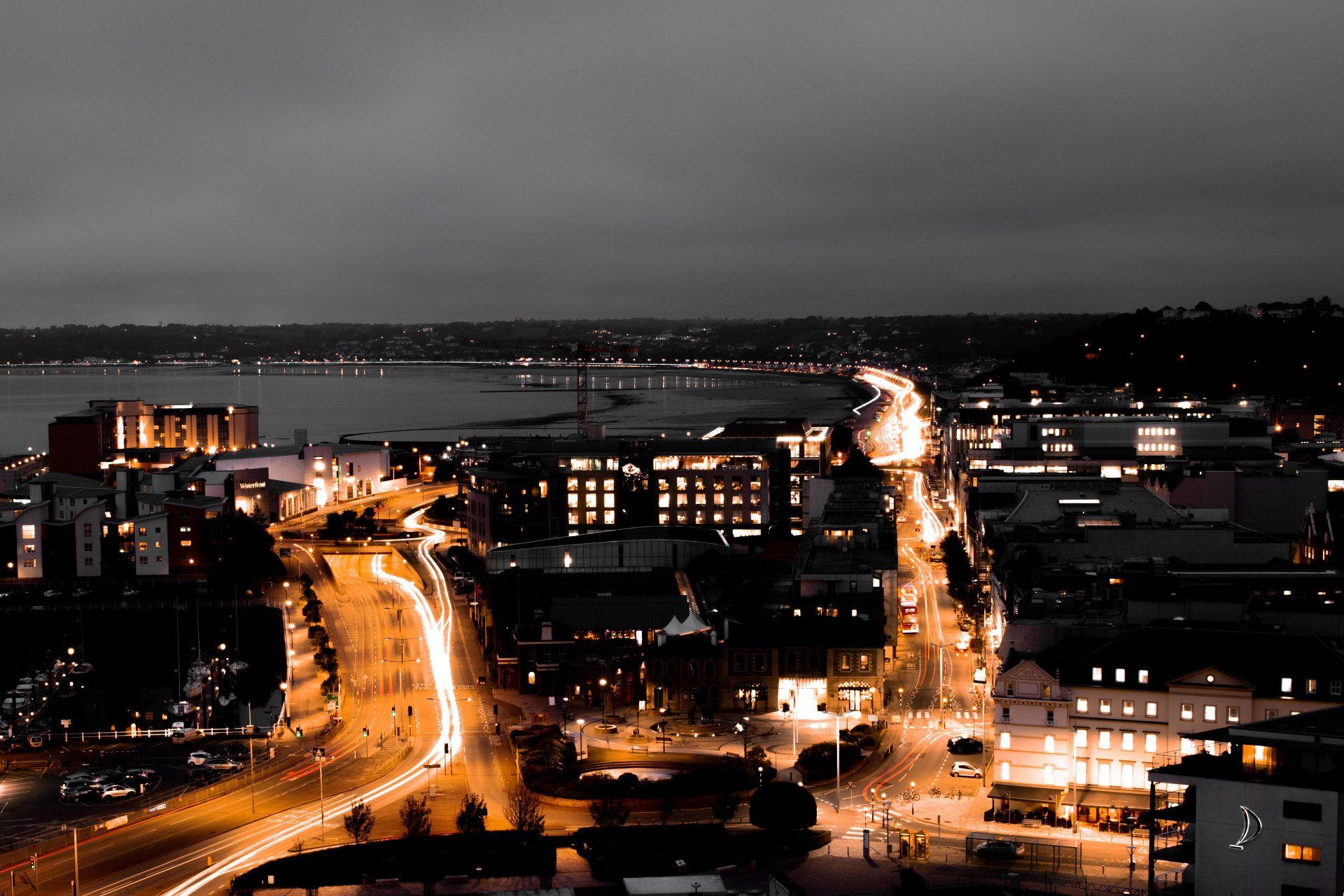 An aerial view of St Helier at night in Jersey with a body of water in the background