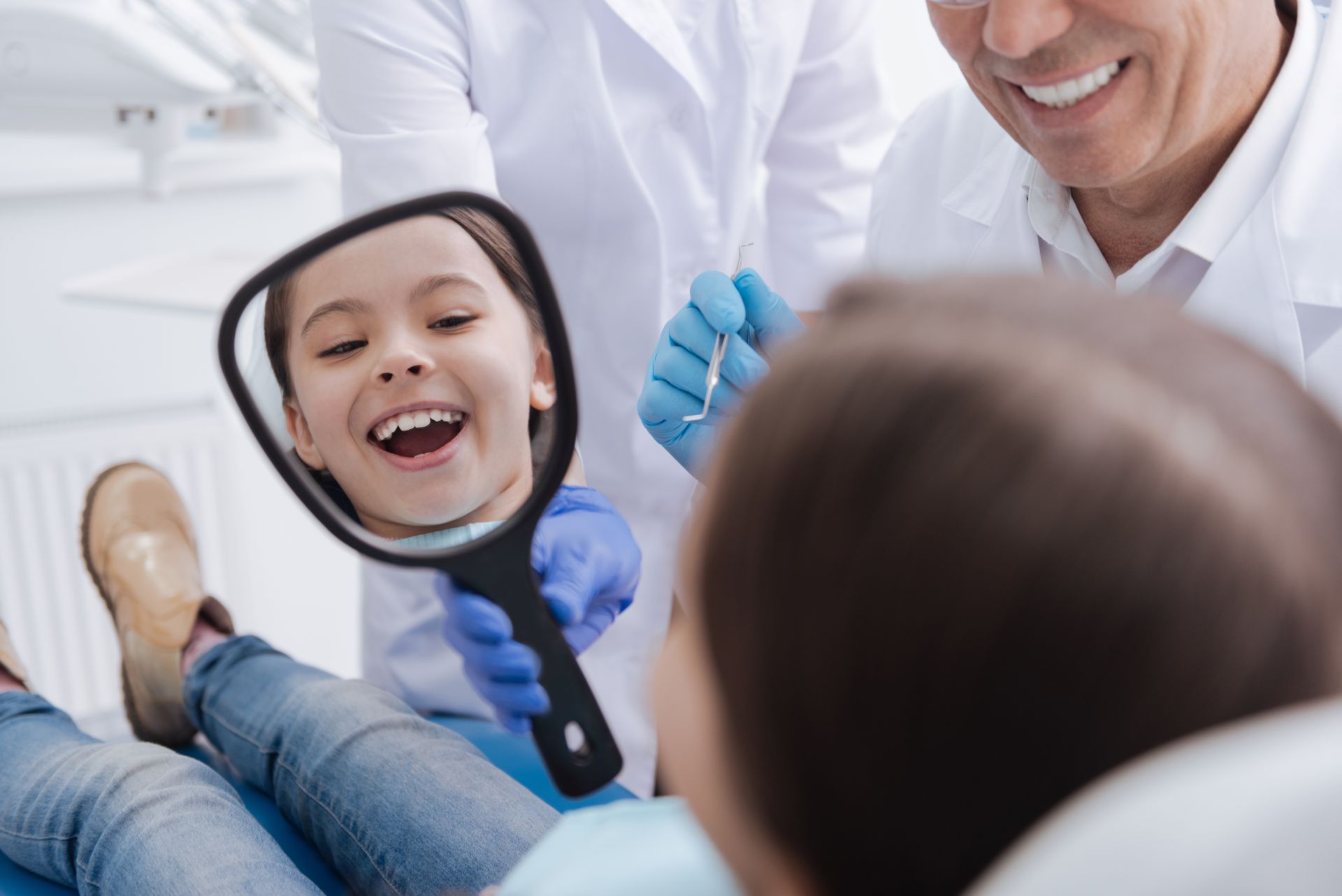 A happy little patient watching herself in the mirror at a family dentist's office. A happy little patient watching herself in the mirror at a family dentist's office.