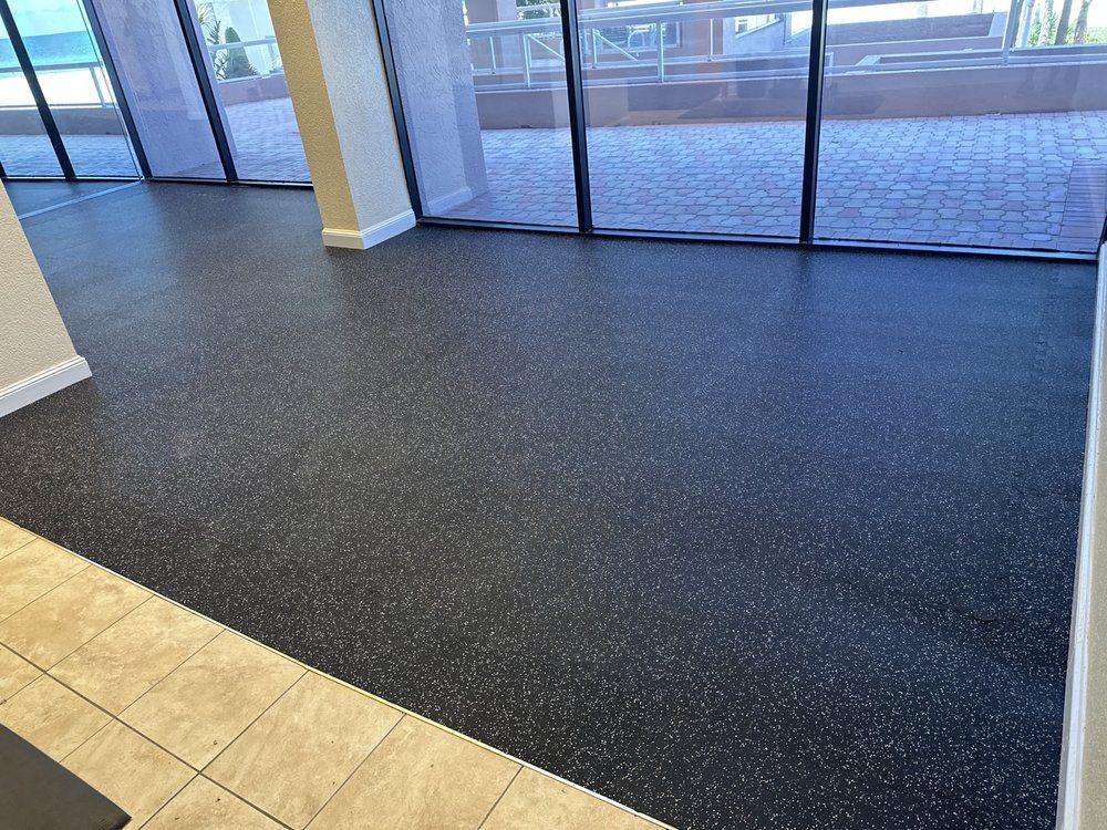 A room with a black rubber floor and a large window.