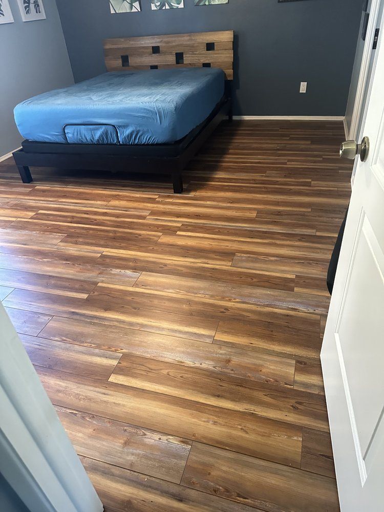 A bedroom with hardwood floors and a bed.