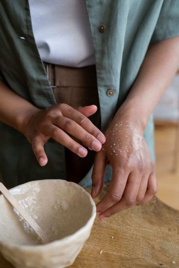 Hands shaping dough on a floured table beside a bowl of batter