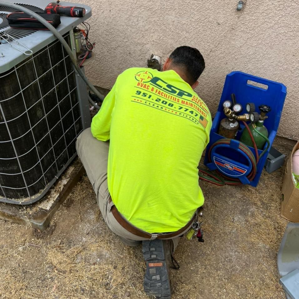 A man in a neon yellow shirt is working on an air conditioner