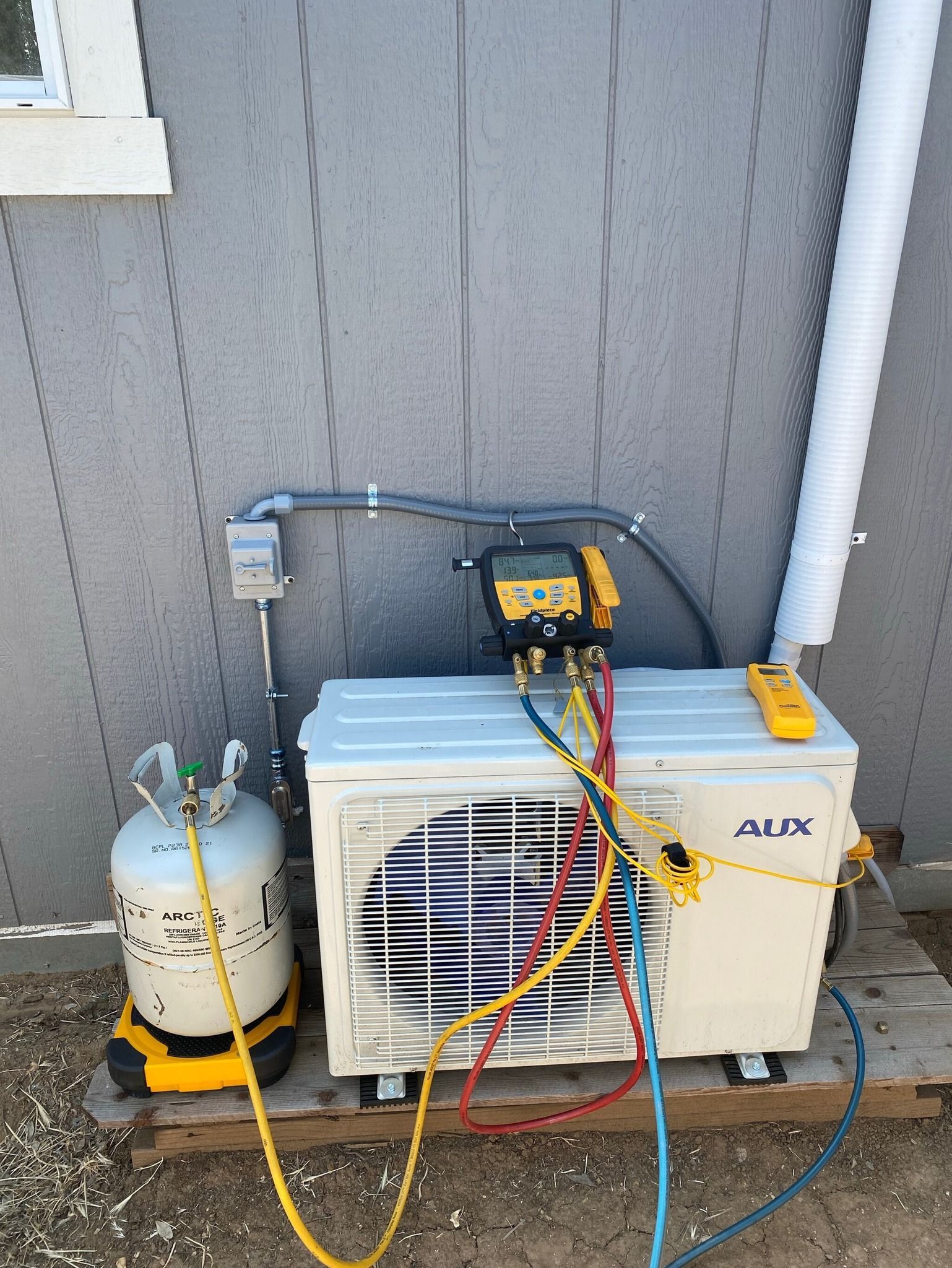 An air conditioner is being serviced outside of a building.