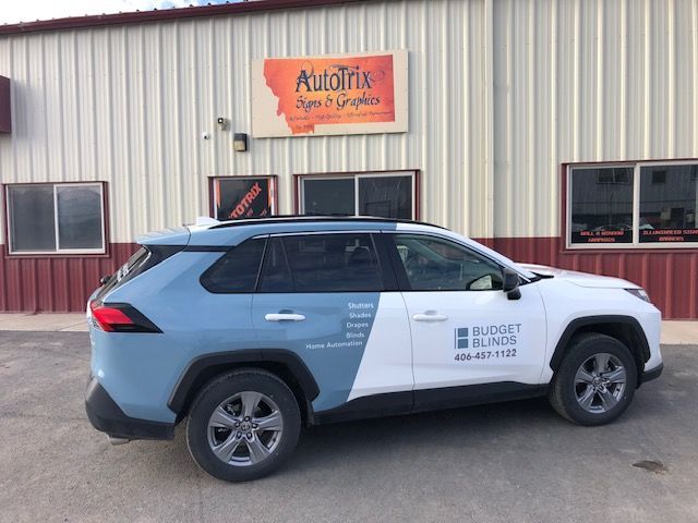SUV with blue and white wrap, parked in front of Autofix Signs & Graphics building.