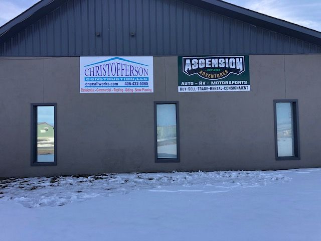 Building with three windows, two business signs, and snow-covered ground. Signs read 