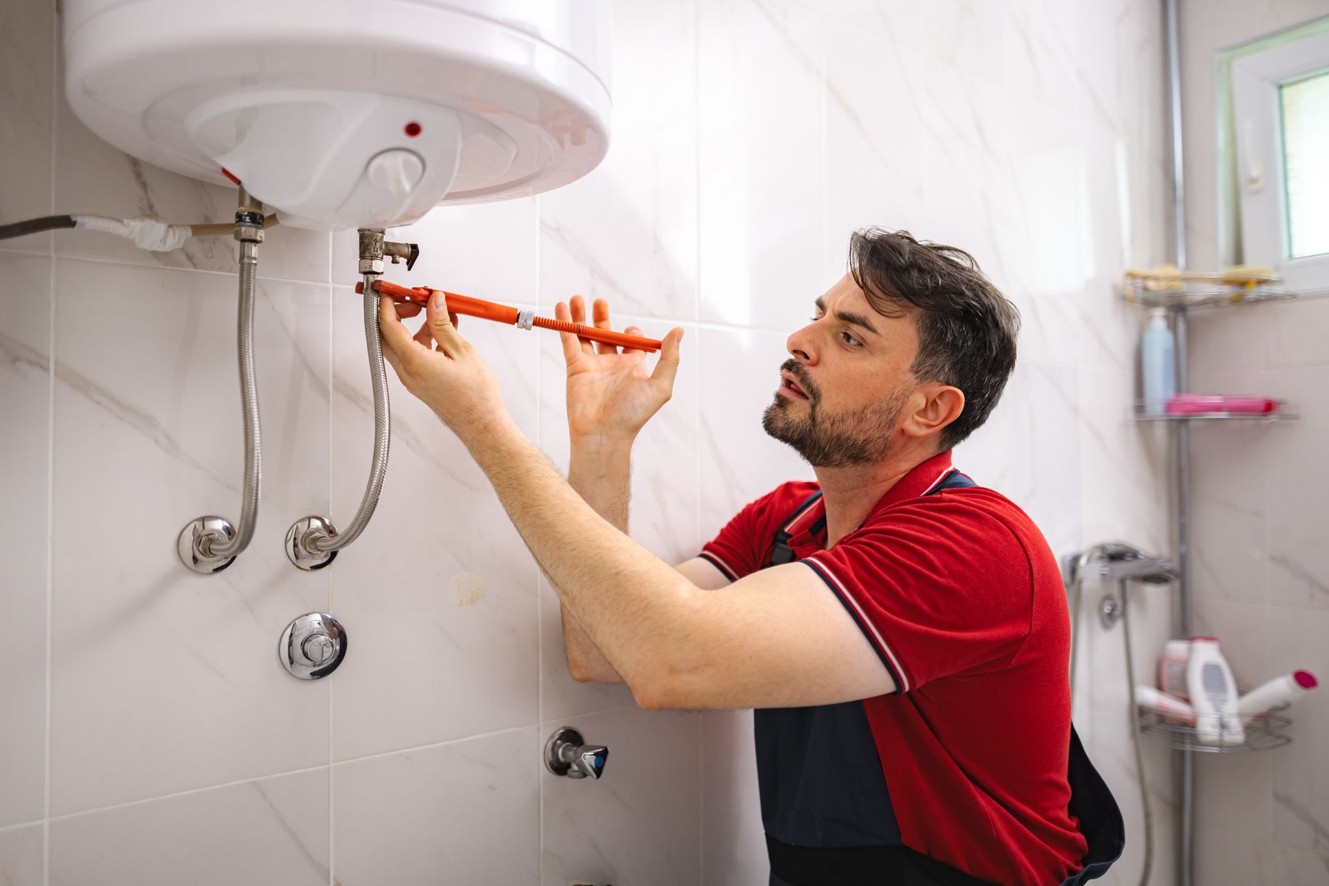 Plumber repairing a wall-mounted water heater in a bathroom. Plumber repairing a wall-mounted water heater in a bathroom.