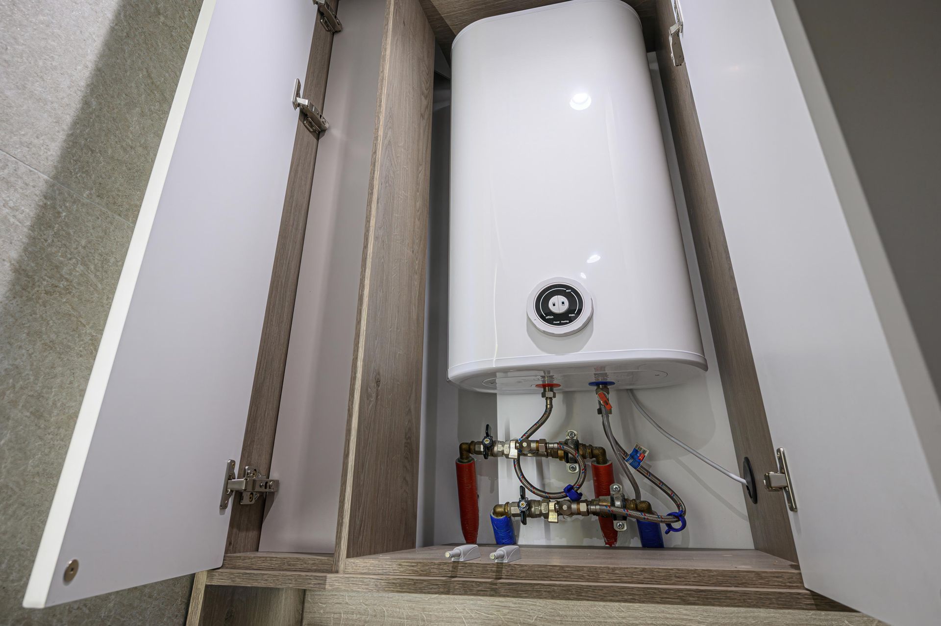 Water heater inside a cabinet with pipes.