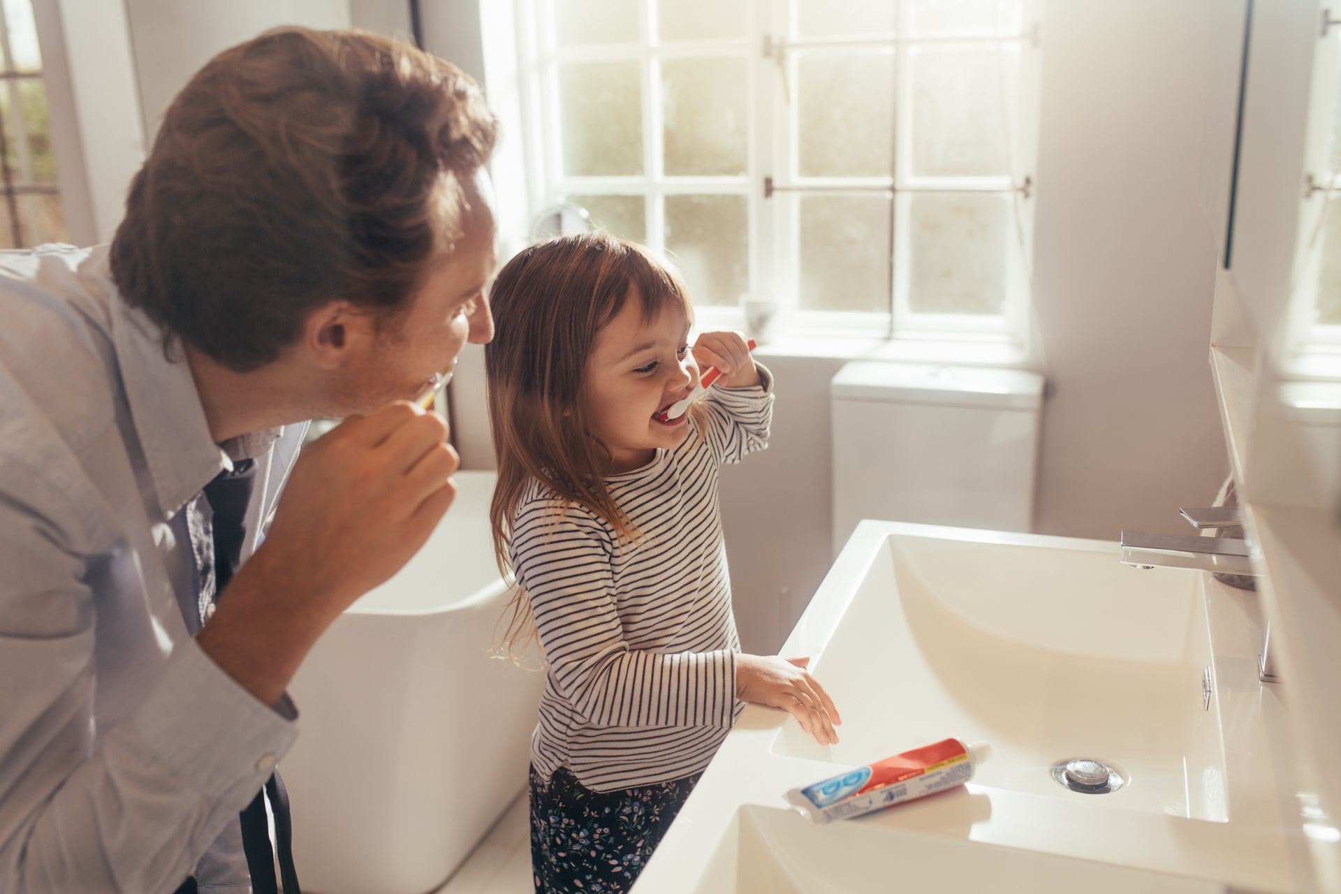 Father and daughter brushing teeth together. Father and daughter brushing teeth together.
