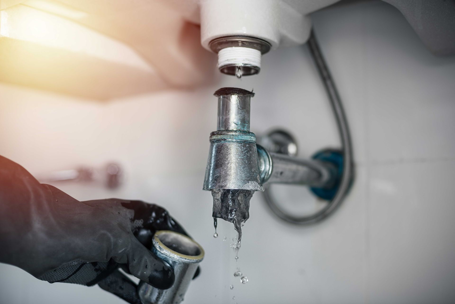 Plumber fixing leaking sink pipe