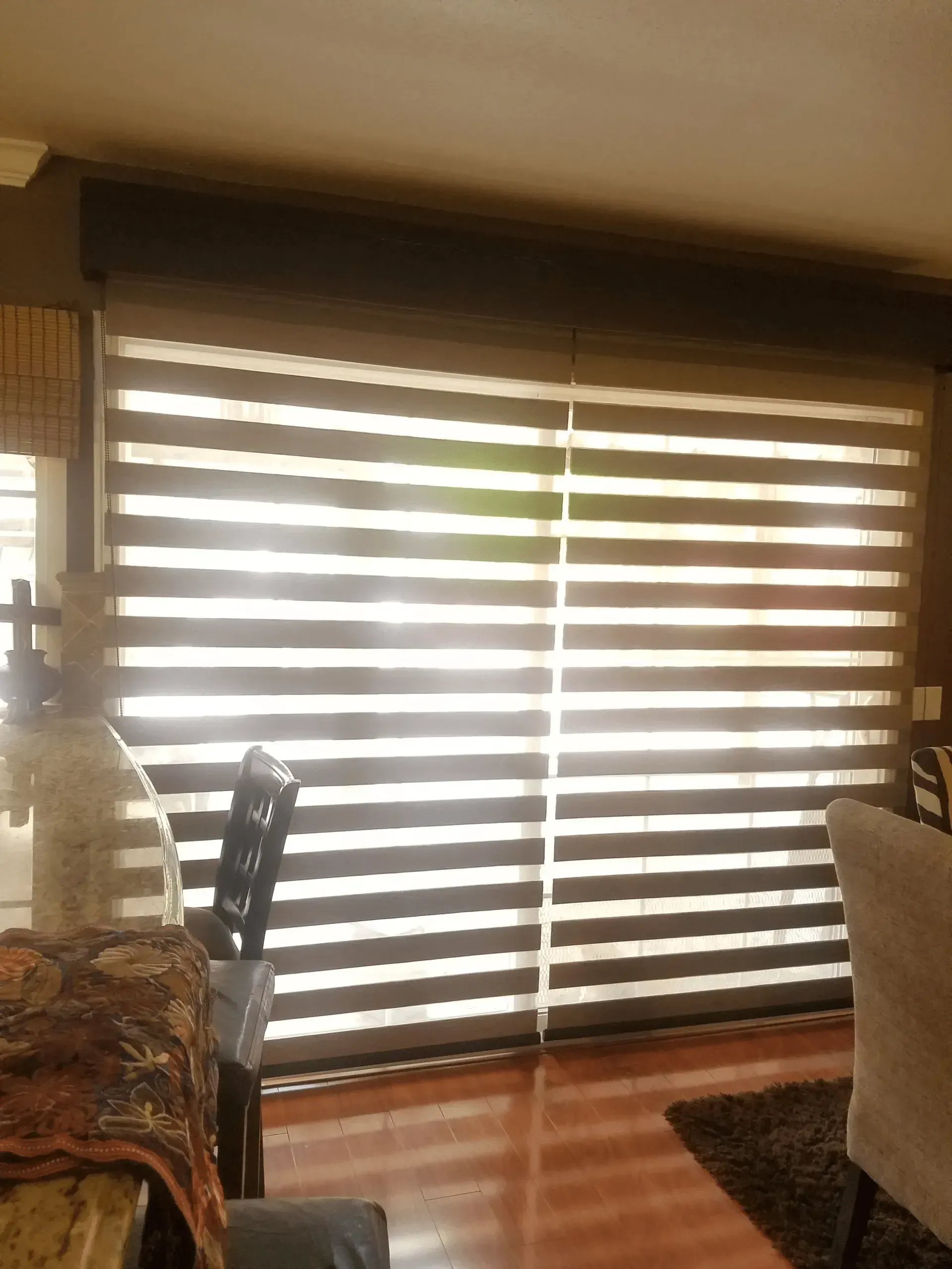 Horizontal striped blinds, filtering light in a room. Brown and white stripes.