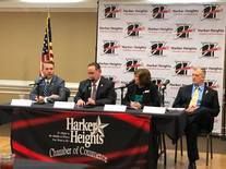 A group of people are sitting at a table in front of microphones.