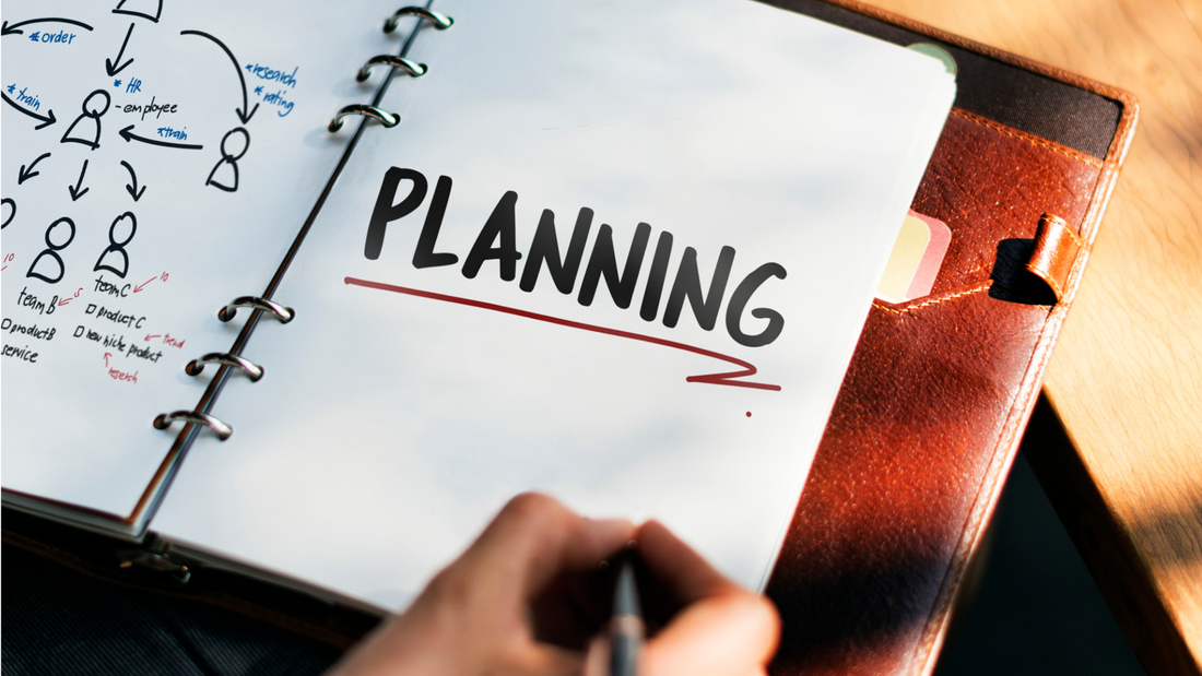 A person is writing in a notebook with the word planning written on it.