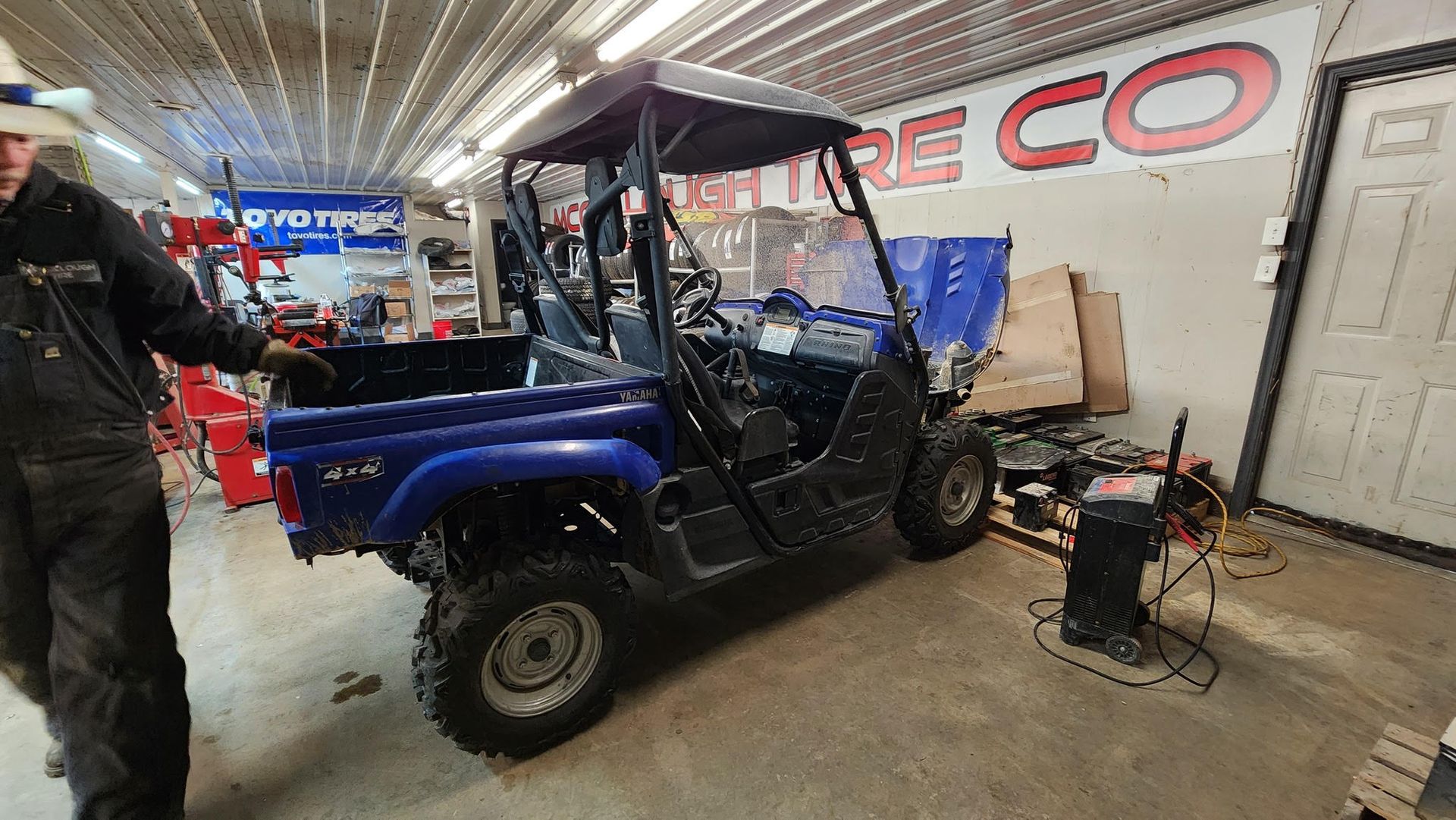 Blue UTV in a garage; a person stands nearby.