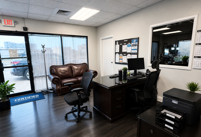 Empty office lobby with leather chairs, desk, computer, and black filing cabinets.
