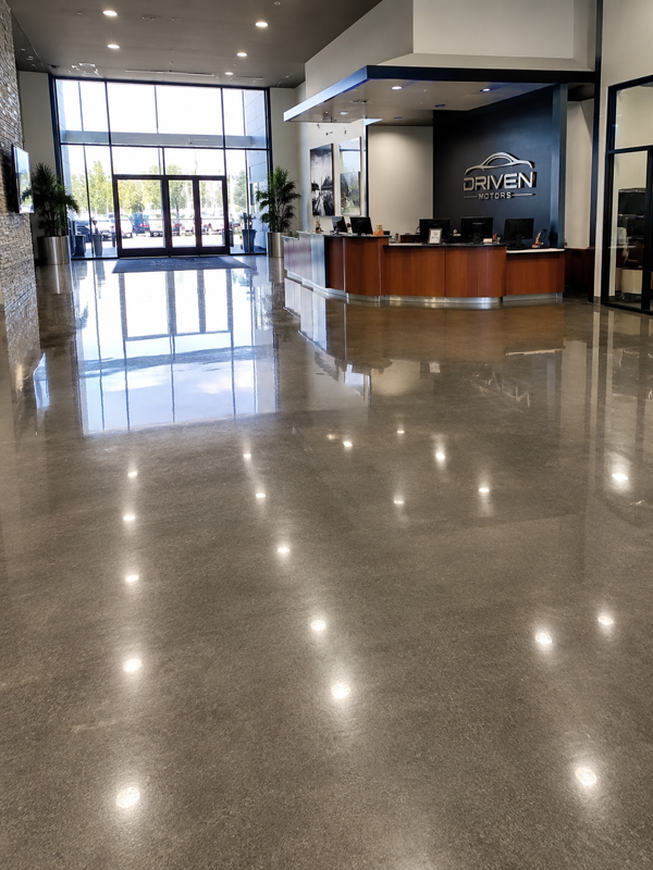 Empty modern lobby with polished floors, reception desk, and glass entrance doors