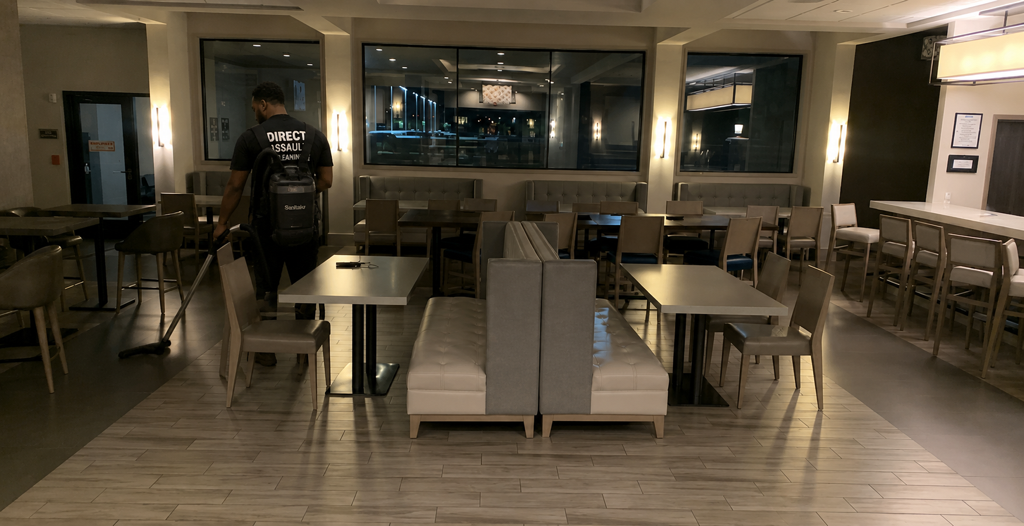 Empty restaurant dining room with tables and chairs, warm lighting, and a central seating booth.