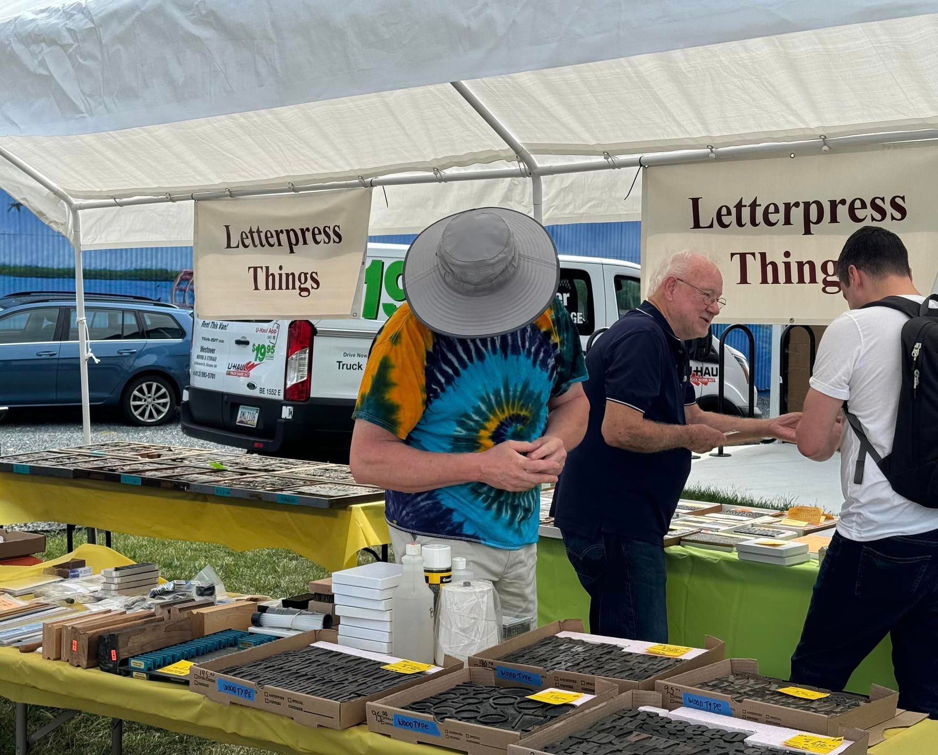 A man in a hat is standing in front of a sign that says letterpress things