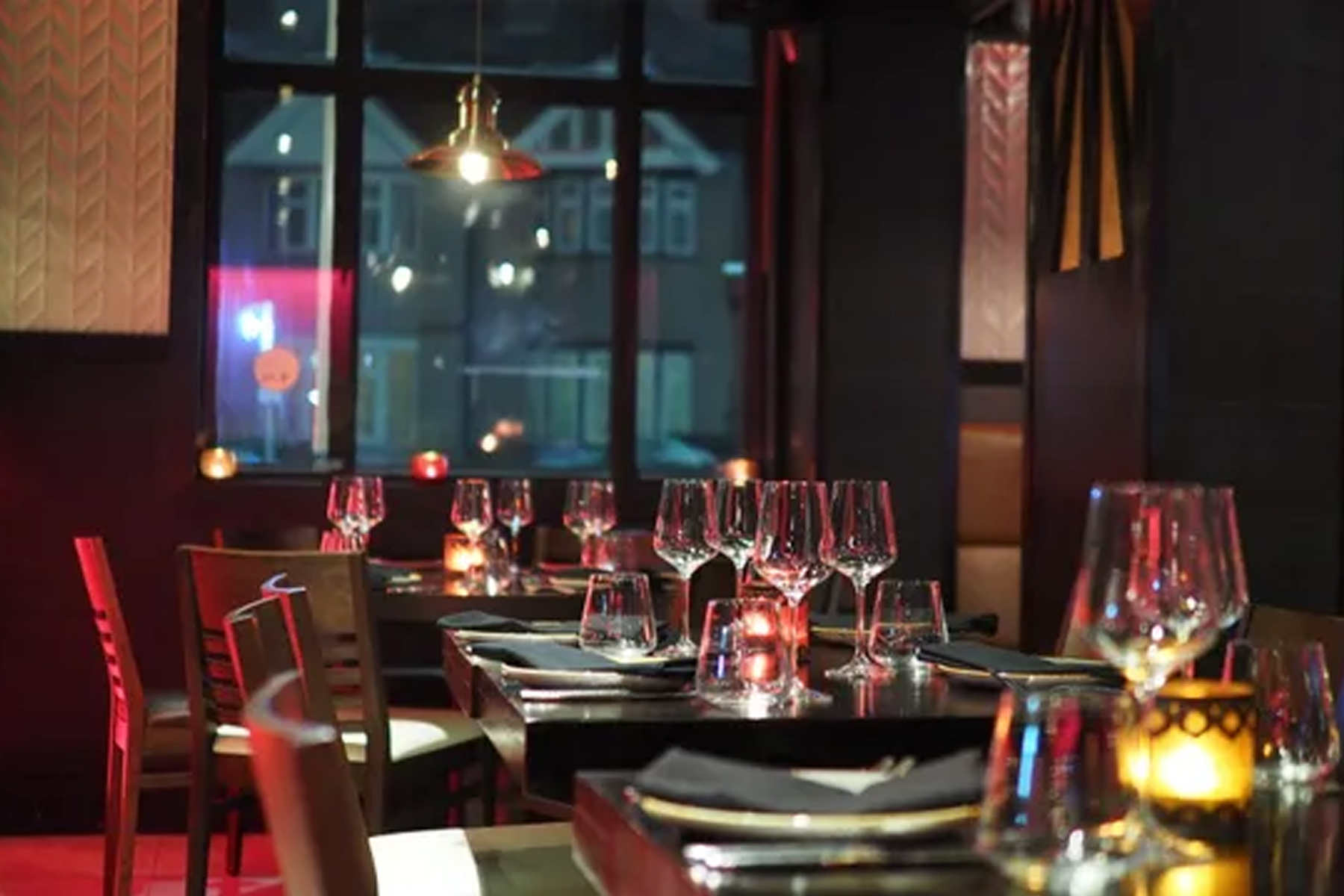 A restaurant with a lot of wine glasses on the tables